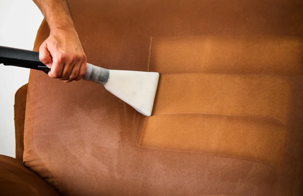 Upholstery tool cleaning a tan fabric sofa